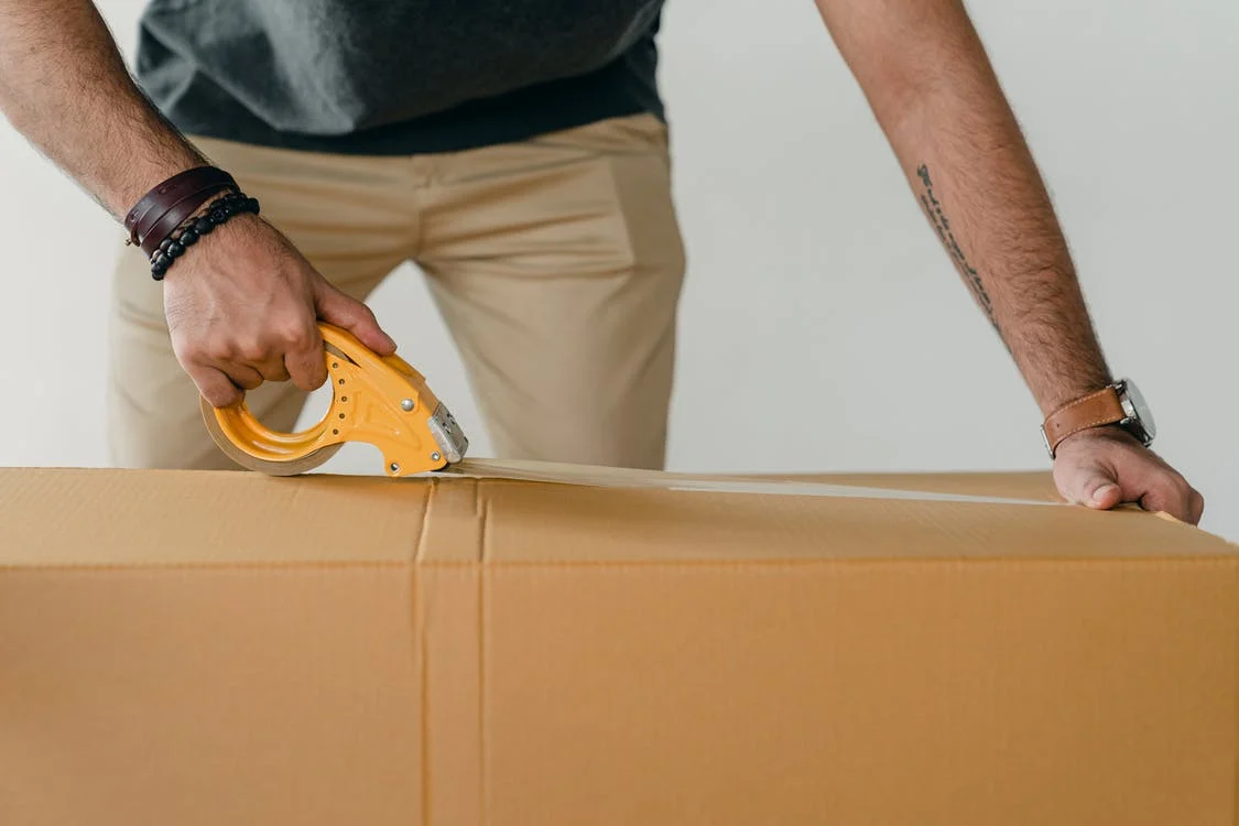 A worker is packing a box. He is an essential part of optimizing warehouse operations.